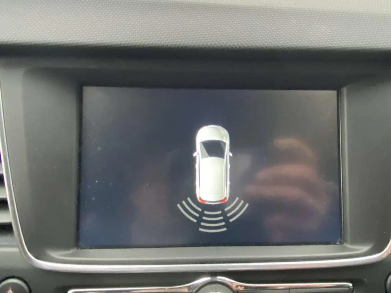Écran central affichant l’aide au stationnement arrière d’une Opel Crossland X, vue en plan du véhicule blanc.