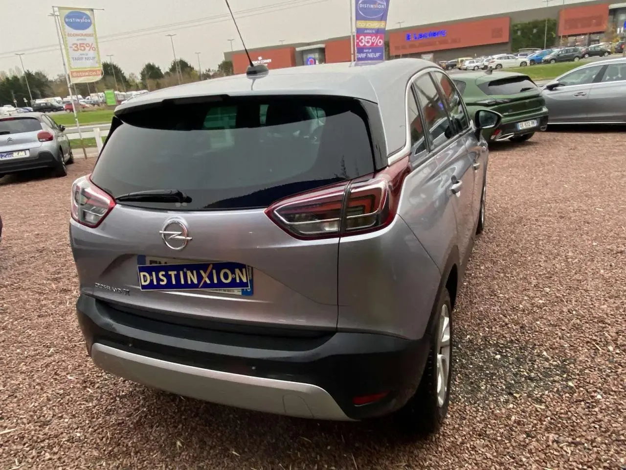 Vue 3/4 arrière d'un Opel Crossland X gris métallisé avec jantes alliage 16'' et vitres surteintées en extérieur.