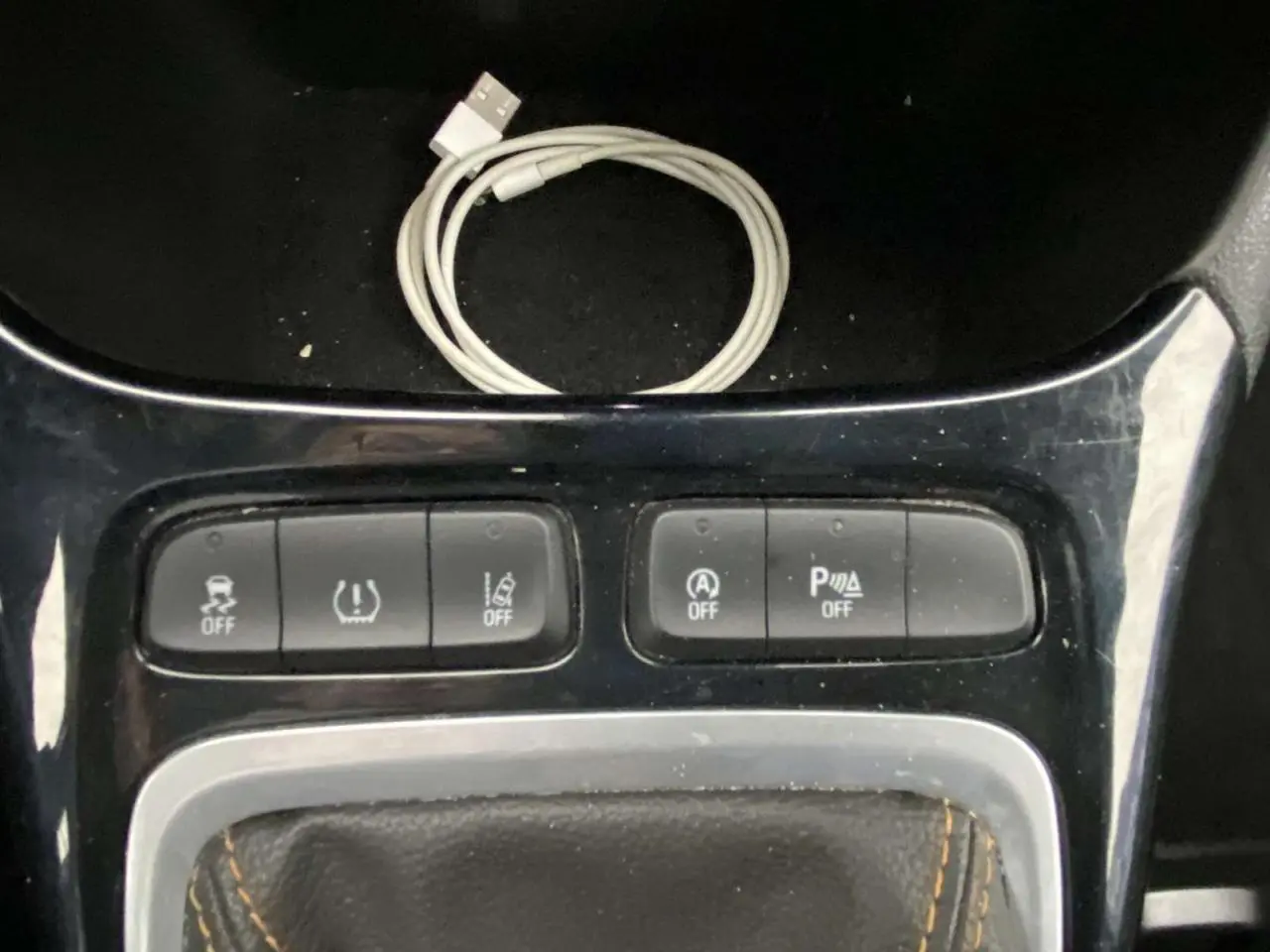 Gros plan sur la console centrale de l’Opel Crossland X 2020, montrant les boutons de contrôle et un câble USB blanc.