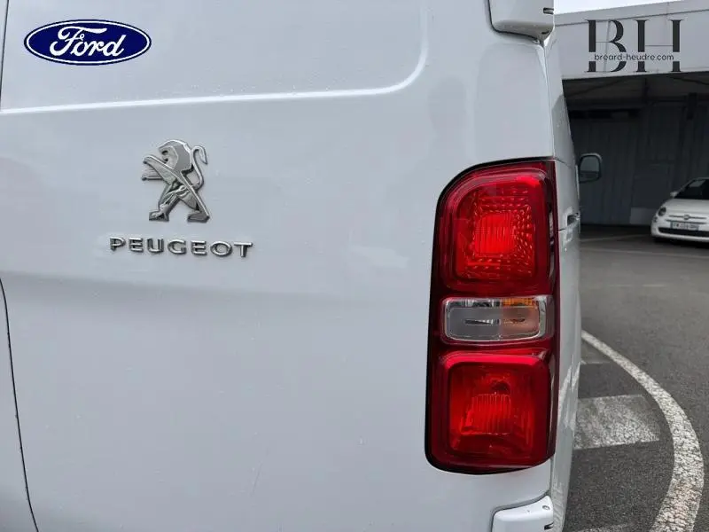 Gros plan sur le feu arrière droit et le logo Peugeot d’un Expert Fourgon blanc Banquise, vue arrière latérale.