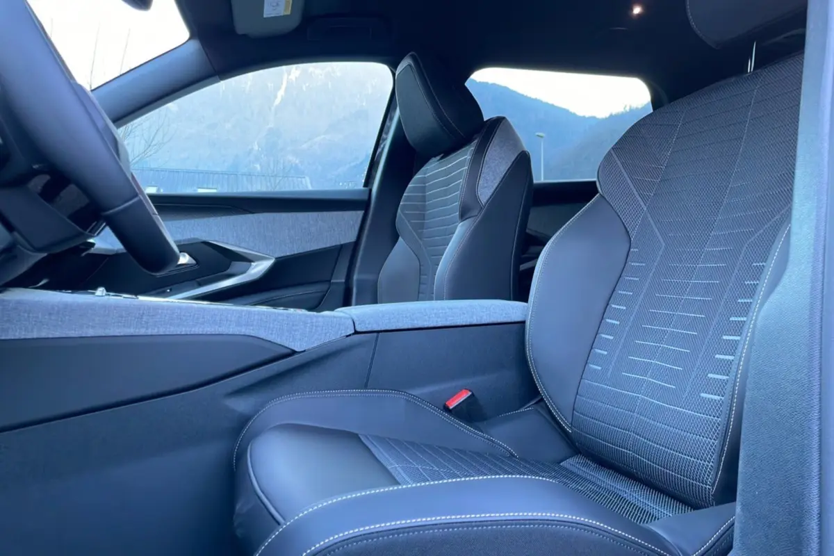 Vue intérieure côté conducteur du Peugeot 5008 Hybrid 145 Allure Plus, sièges cuir tissu gris avec surpiqûres blanches.