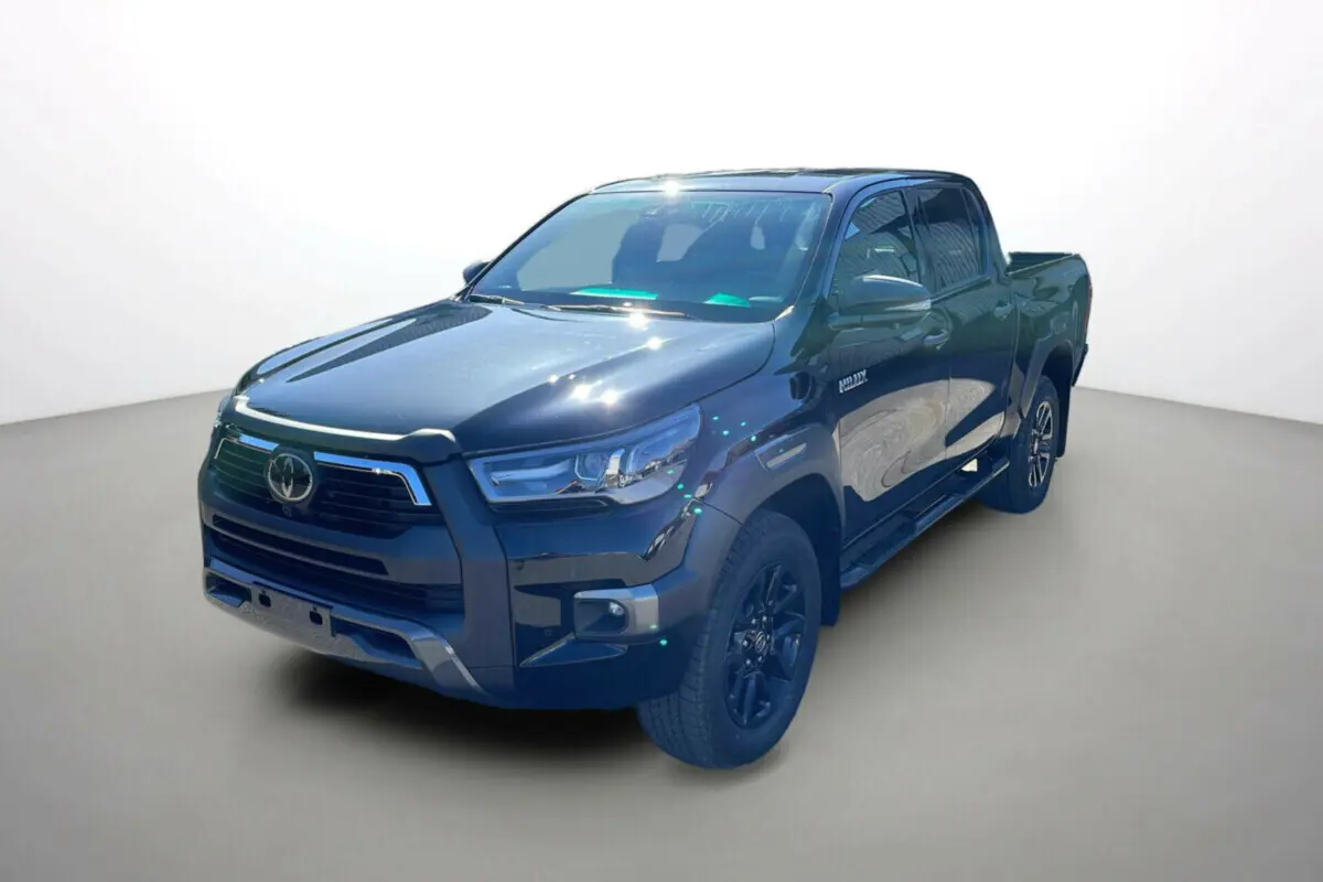 Toyota Hilux 4x4 noir attitude en 3/4 avant droit, mettant en valeur sa calandre et ses jantes noires robustes.