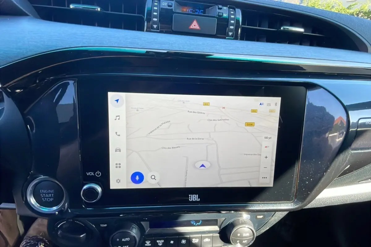 Écran tactile central avec navigation GPS et commandes climatisation dans le tableau de bord du Toyota Hilux 2025 Noir Attitude.