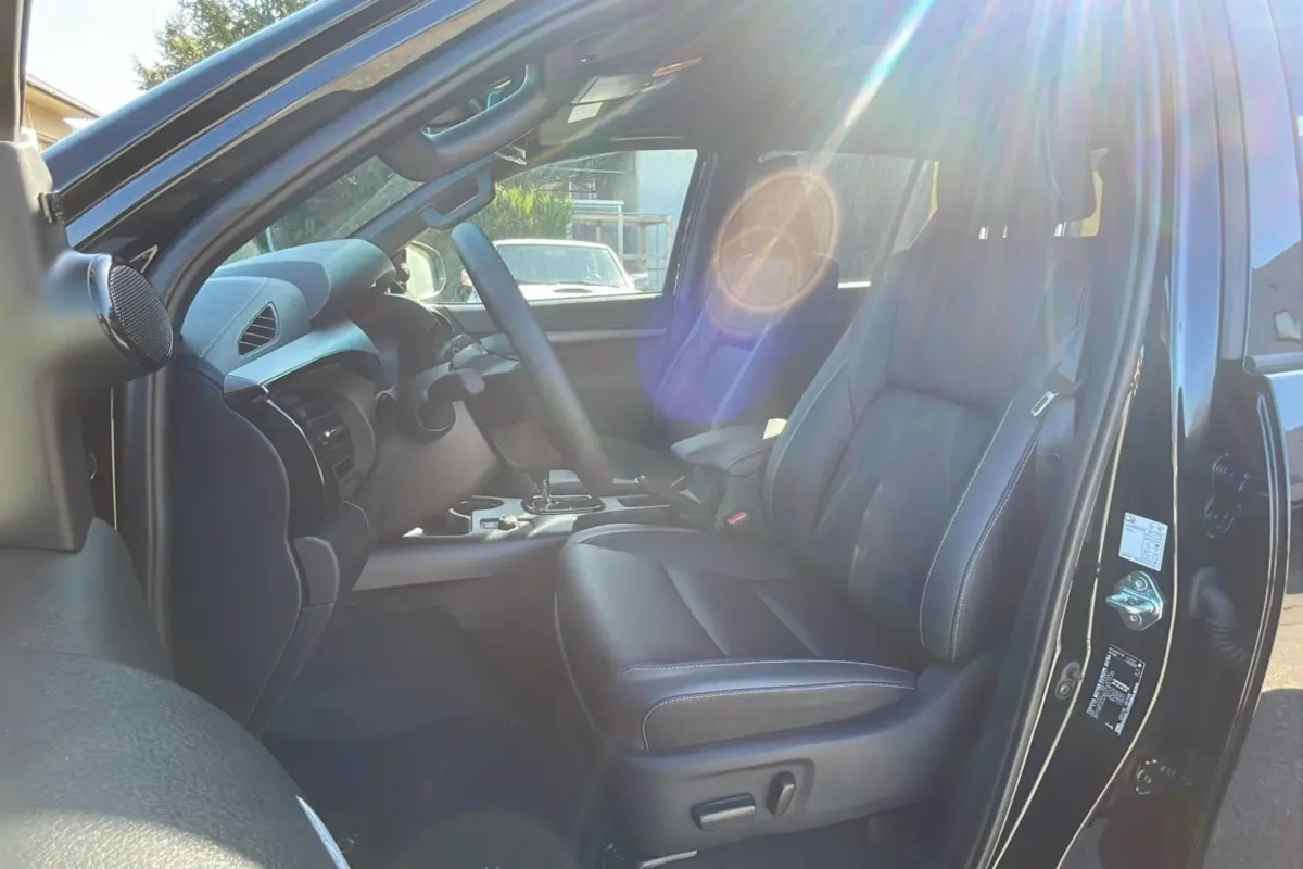 Intérieur du Toyota Hilux 2025 noir attitude, vue côté conducteur avec sièges cuir et tableau de bord moderne.