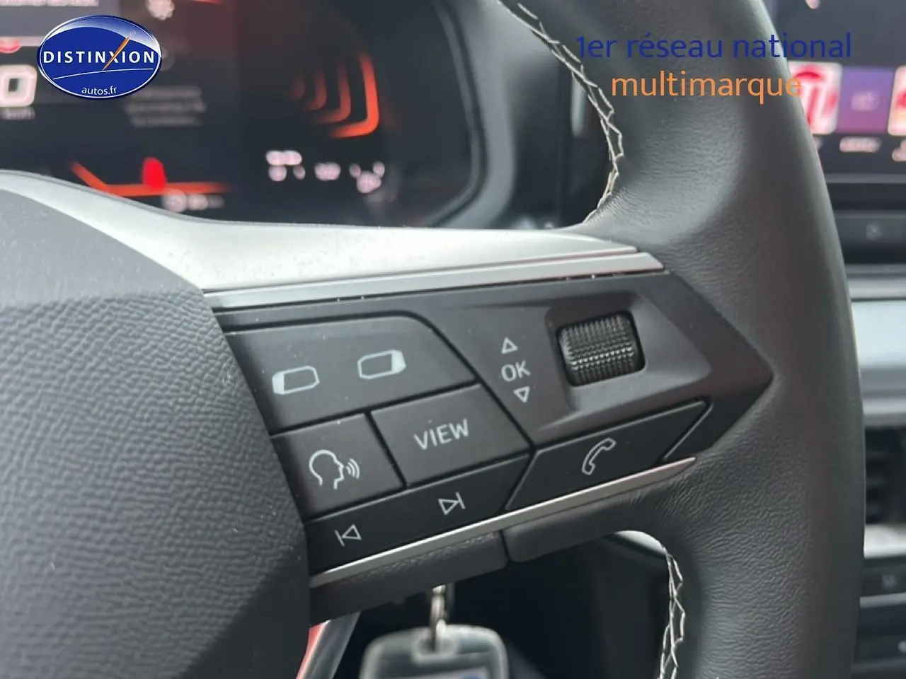 Gros plan sur les commandes multifonctions du volant cuir noir du SEAT Arona 2025, avec affichage digital en arrière-plan.