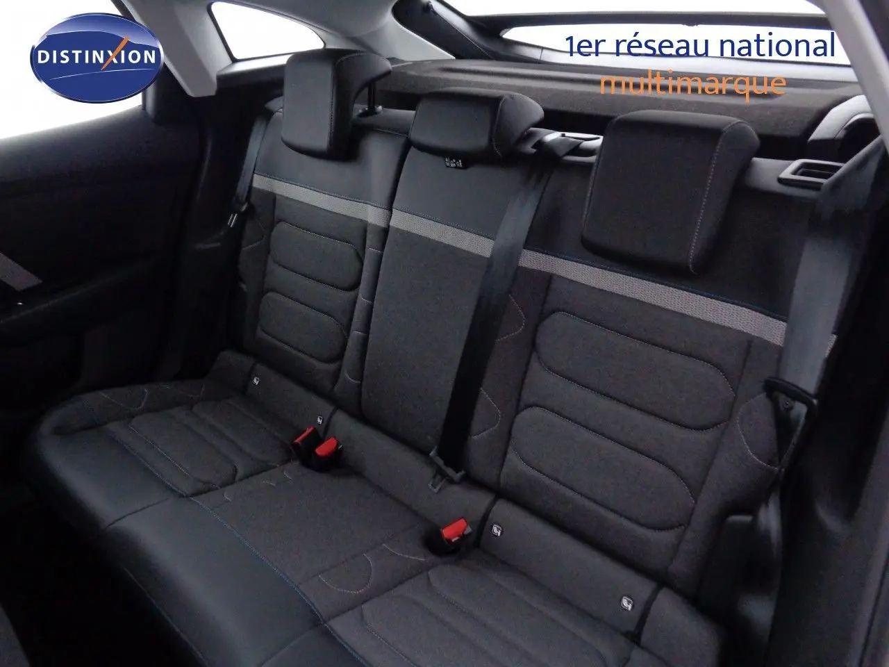 Vue intérieure arrière des sièges arrière gris foncé de la Citroën C4 2023 avec appuie-têtes et ceintures visibles.