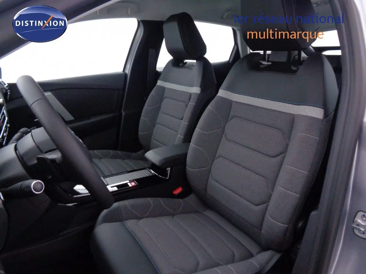 Vue intérieure côté conducteur de la Citroën C4 2023 gris Artense, sièges tissu et cuir noir avec surpiqûres bleues.