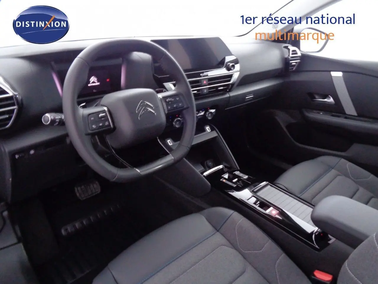 Intérieur de la Citroën C4 2023 en gris, vue côté conducteur montrant le tableau de bord et la console centrale moderne.