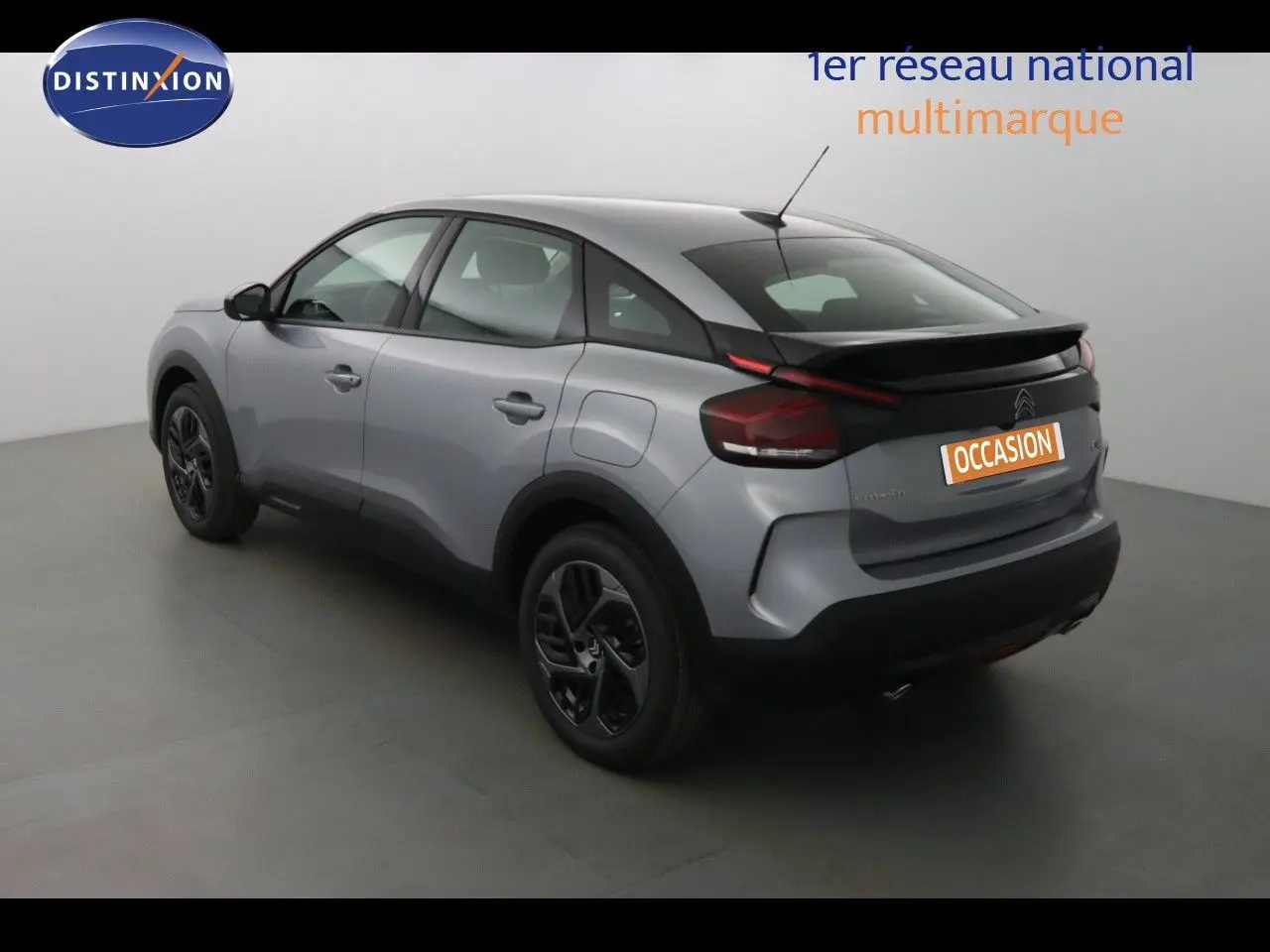 Vue 3/4 arrière droite d'une Citroën C4 gris Artense métal avec toit noir et jantes noires dans un studio.