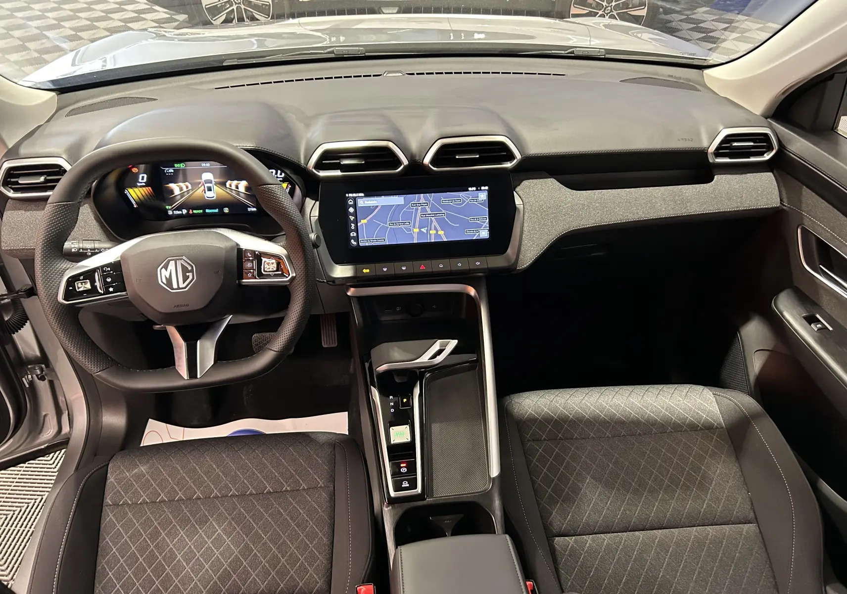Vue intérieure avant du MG ZS Cosmic Silver 2025, avec tableau de bord numérique et écran tactile central affichant la navigation.