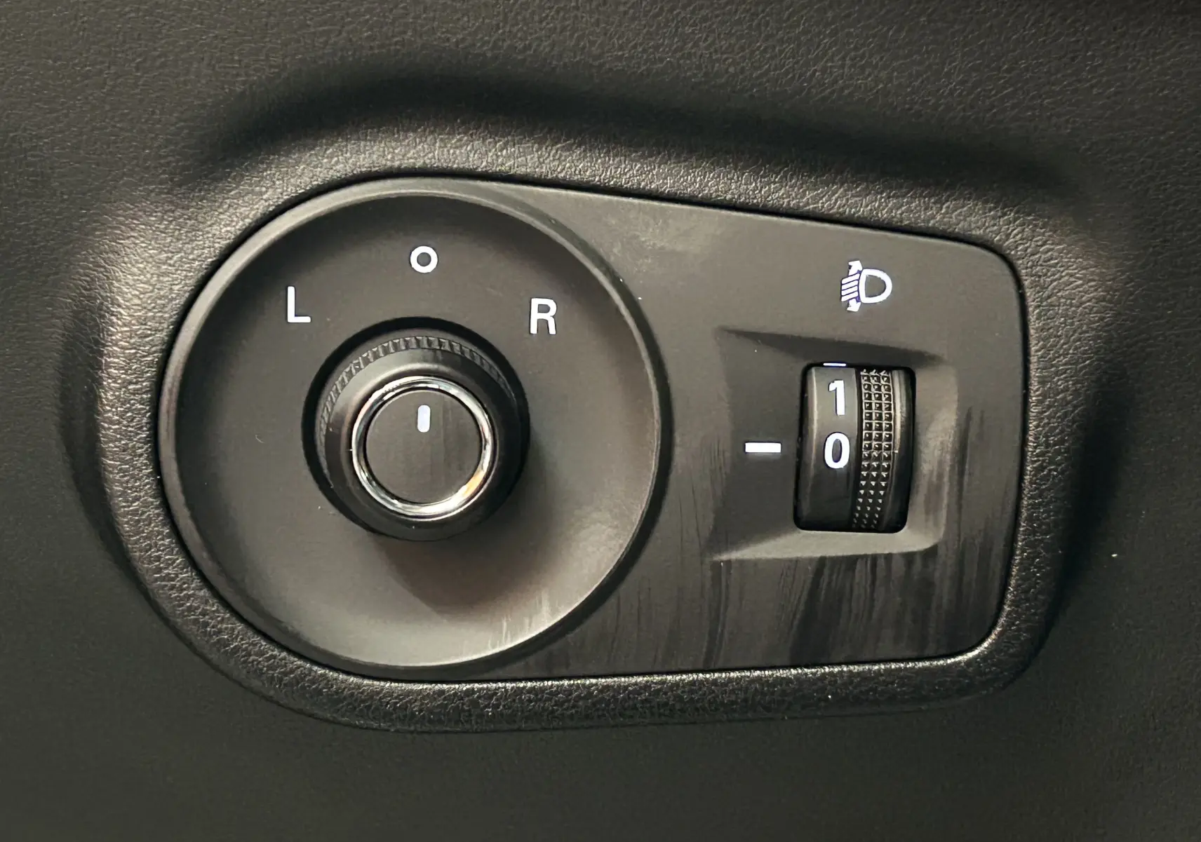Gros plan sur la commande de réglage des rétroviseurs et des phares du MG ZS Cosmic Silver 2025.