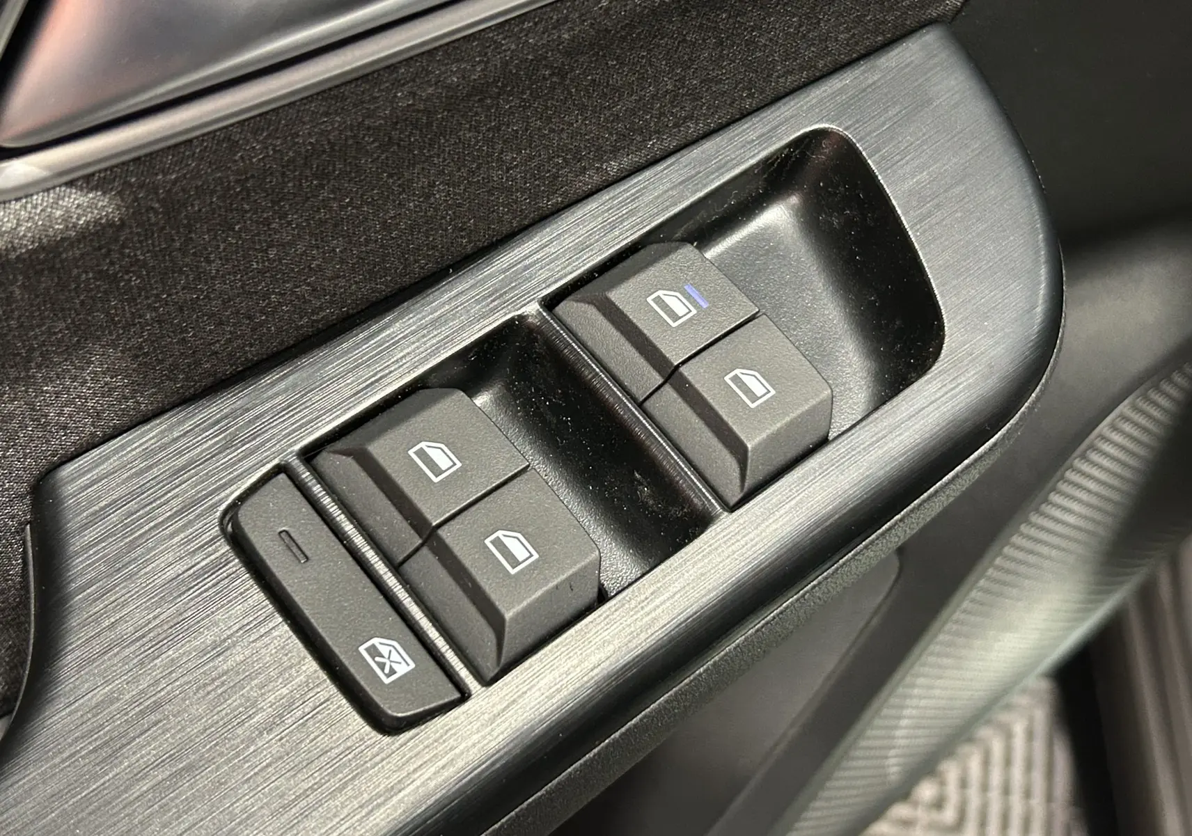 Gros plan sur les commandes de lève-vitres côté conducteur du MG ZS Cosmic Silver, finition intérieure noire.