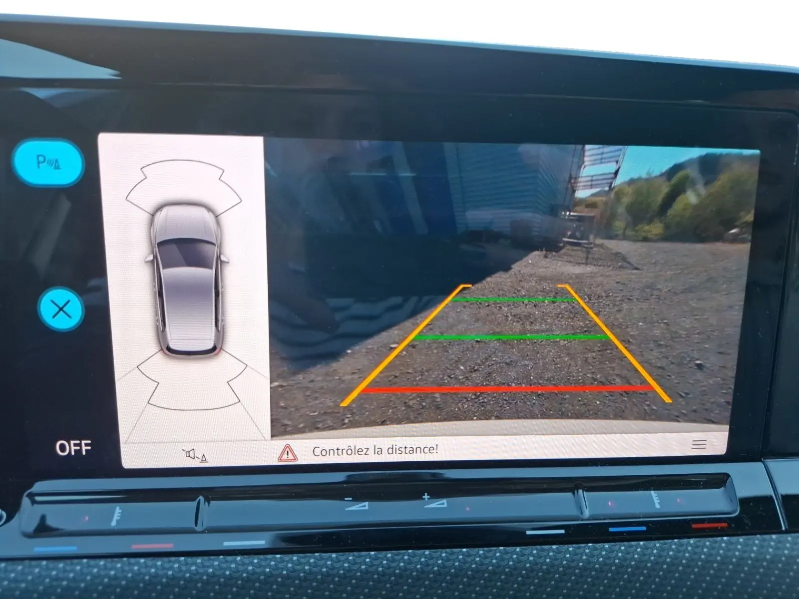 Vue de l'écran de la caméra de recul de la Volkswagen Golf blanche 2023, avec guidage coloré et capteurs de stationnement.