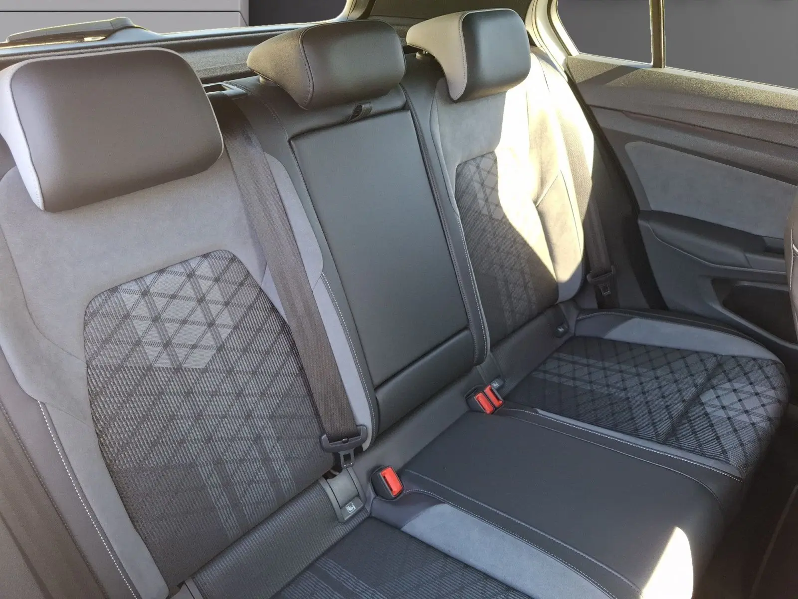 Vue intérieure des sièges arrière en tissu et alcantara avec motifs géométriques dans une Volkswagen Golf blanche 2023.