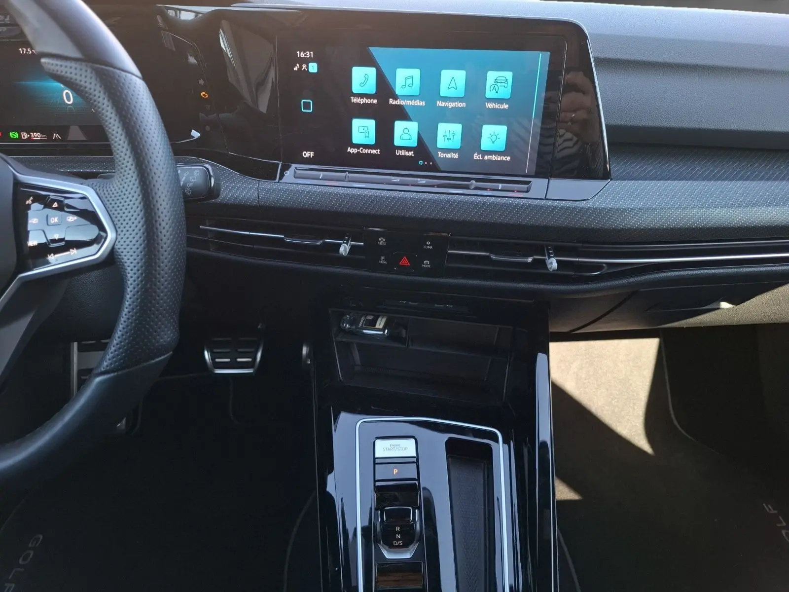 Vue intérieure centrée sur la console et l’écran tactile de la Volkswagen Golf blanche, avec volant et commandes visibles.