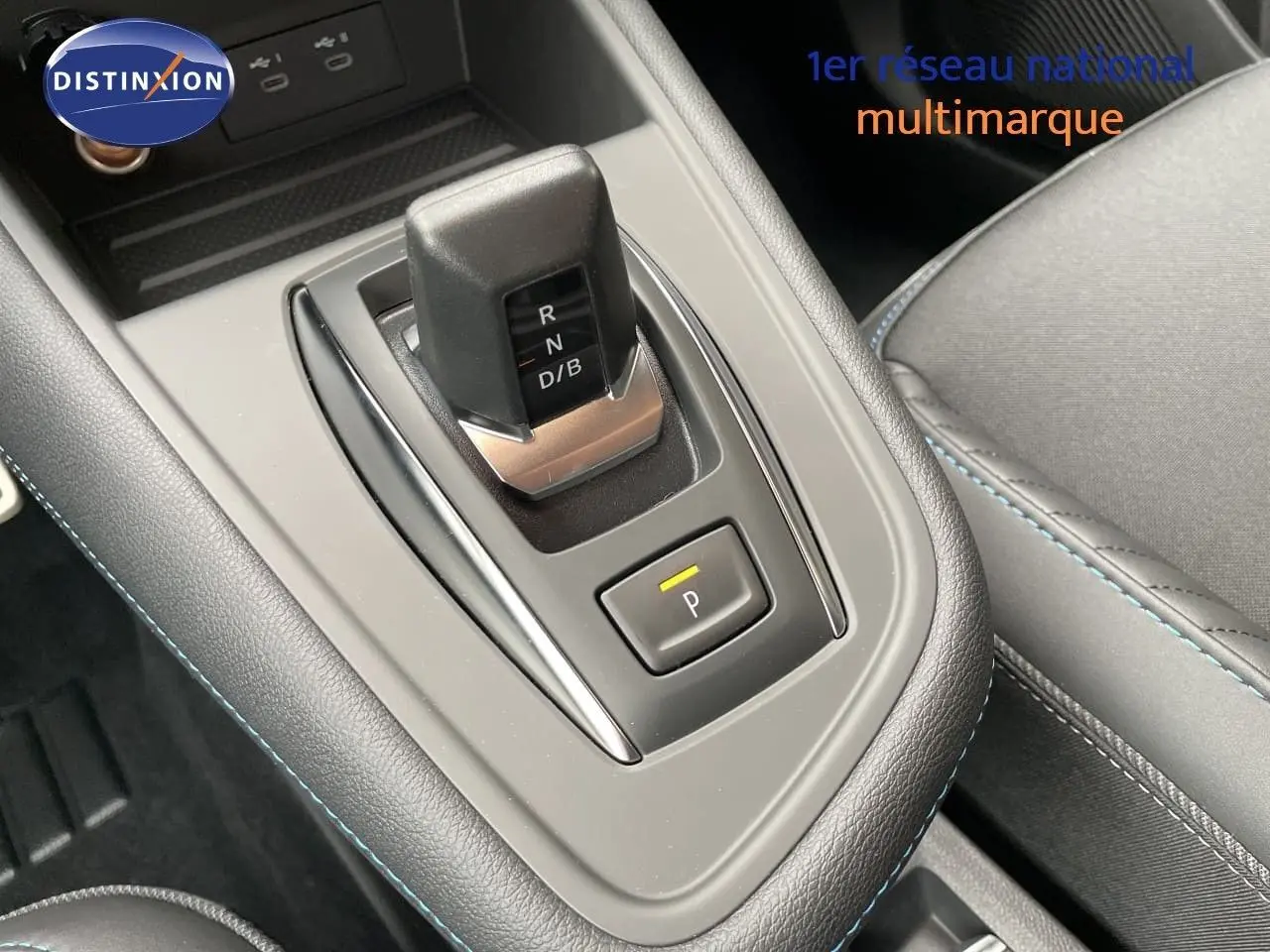 Gros plan sur la console centrale de la Renault Symbioz 2026, avec levier de boîte auto et surpiqûres bleues visibles.