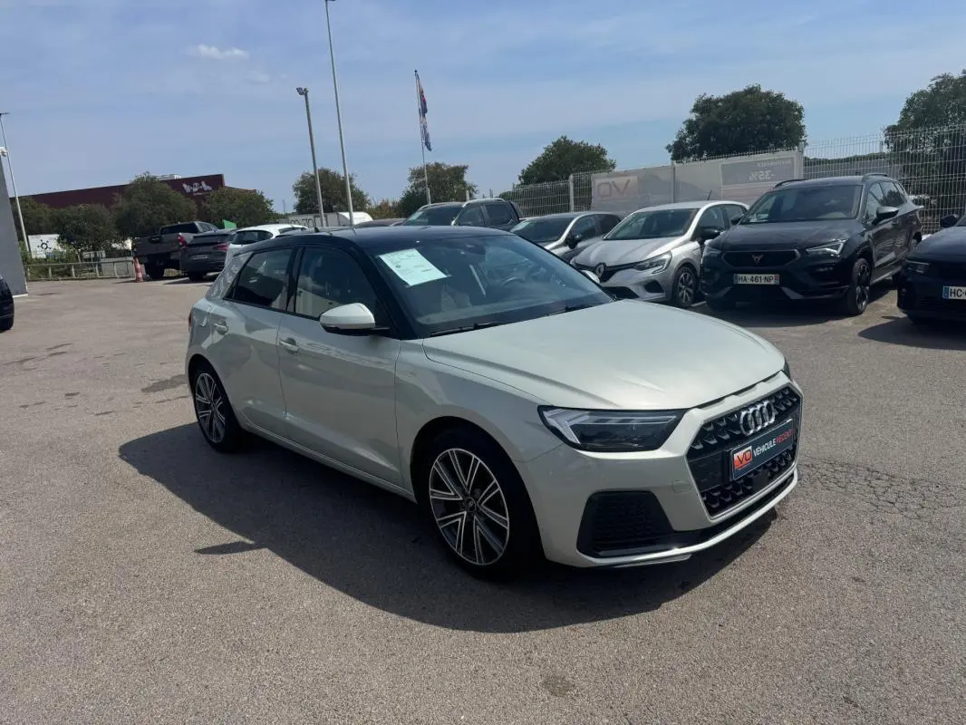 Audi A1 Sportback gris vue 3/4 avant droit sur parking, toit noir contrastant et jantes alliage visibles.