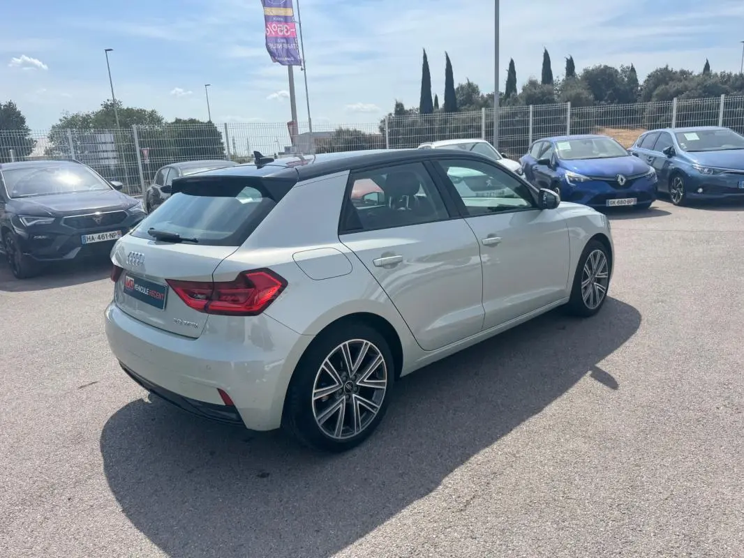 Audi A1 Sportback gris vue 3/4 arrière droit sur parking, avec toit noir et jantes alliage distinctives.