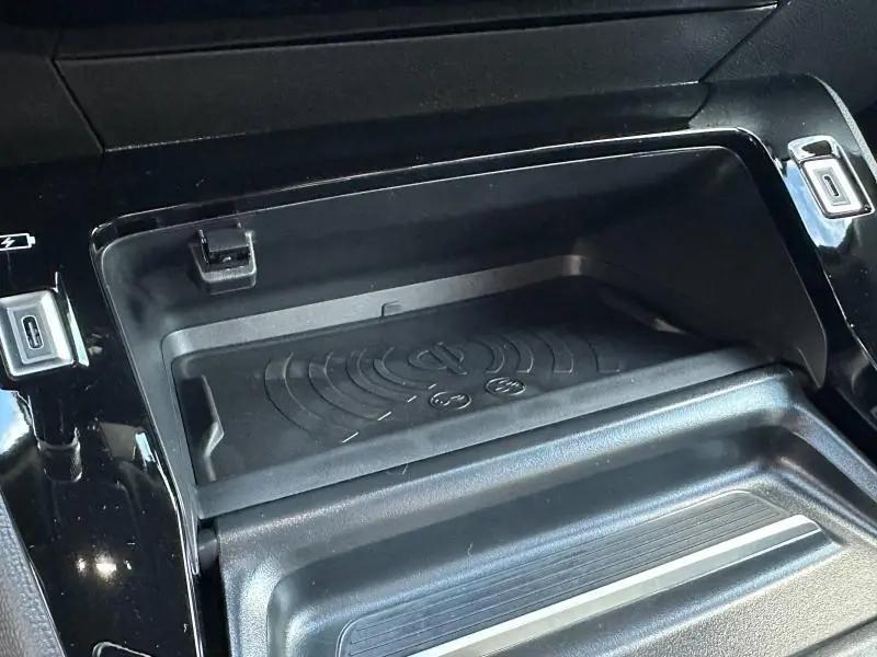 Gros plan sur la zone de recharge sans fil noire et les ports USB du Peugeot 2008 Hybrid 145ch GT 2025.