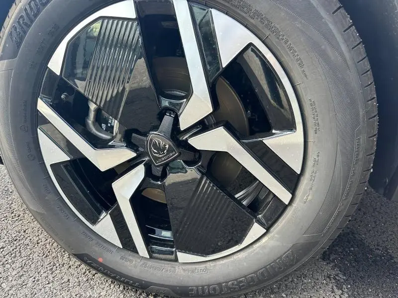Gros plan sur la jante alu noire et argentée du PEUGEOT 2008 bleu, mettant en valeur le logo lion central.