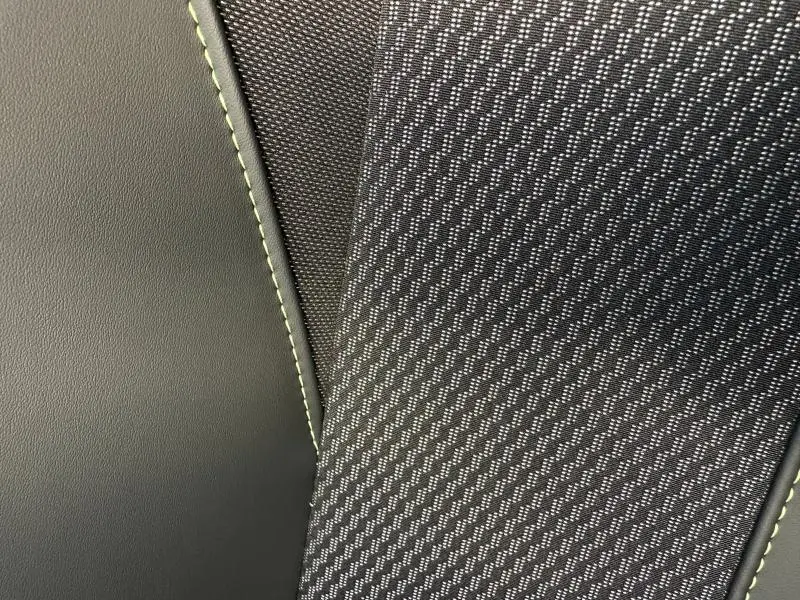Détail du tissu Belomka et cuir noir avec surpiqûres vertes sur siège Peugeot 2008 Hybrid 2025.