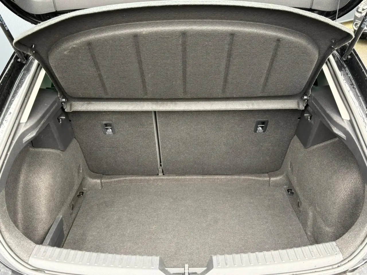 Coffre ouvert vu de l'arrière d'une SEAT LEON 2.0 TDI 150 DSG7 Business noir Minuit, espace de chargement vide et propre.