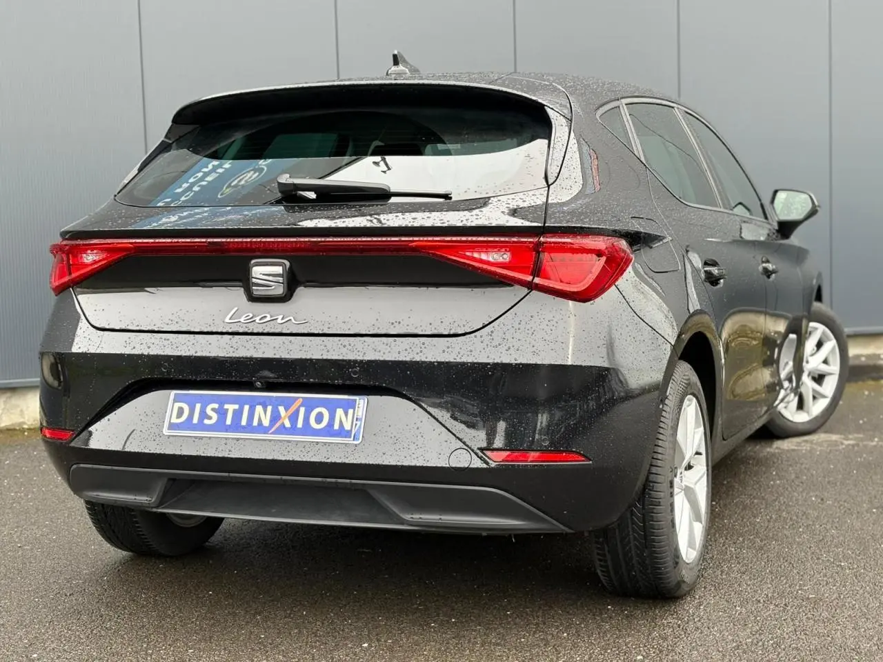 Vue 3/4 arrière droite d'une SEAT Leon 2024 noir minuit avec feux arrière LED et jantes alliage 16 pouces.