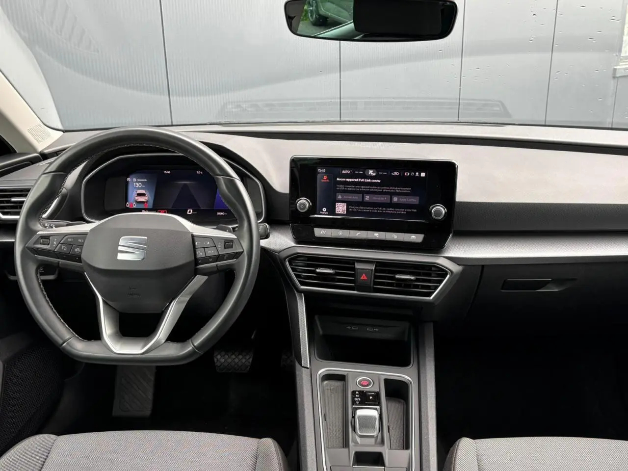 Vue intérieure avant du tableau de bord de la SEAT Leon 2024 avec volant cuir multifonction et écran tactile central.