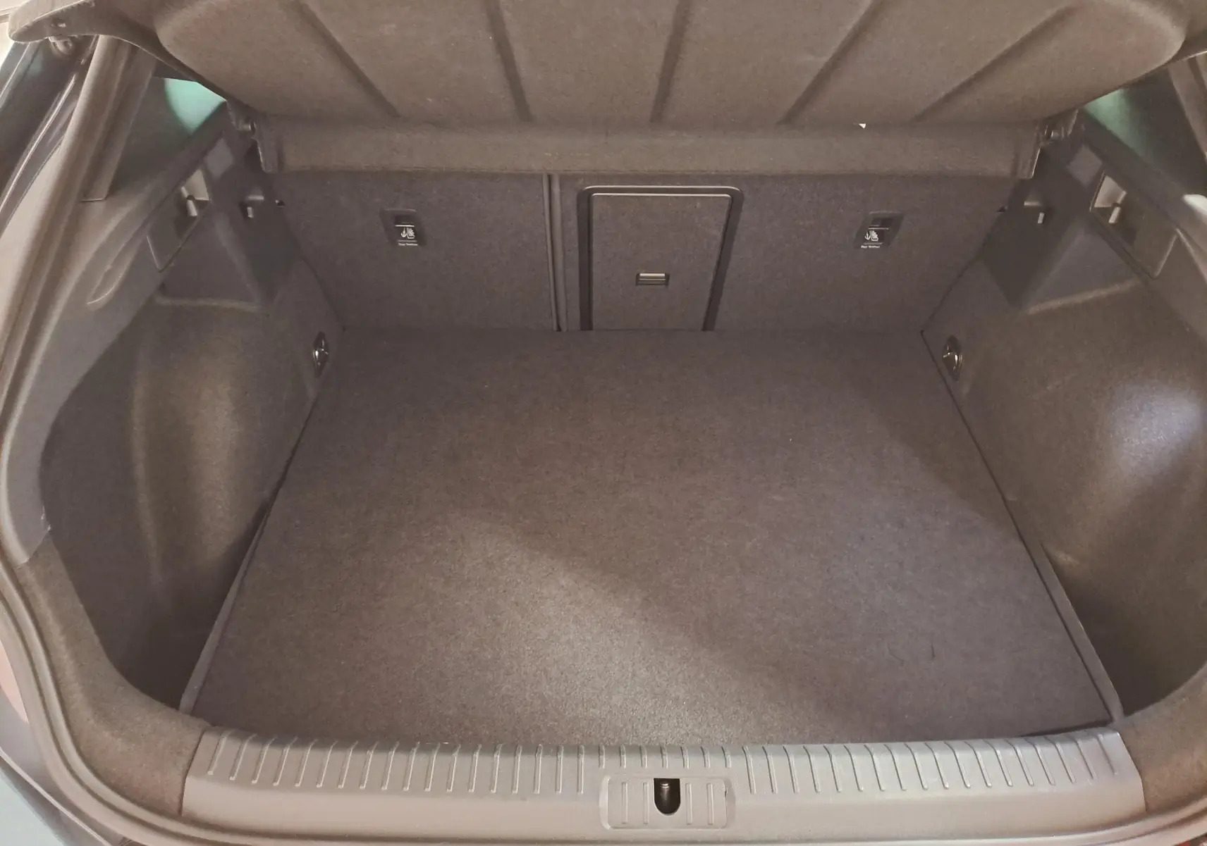 Coffre ouvert vu de l'arrière d'un CUPRA Formentor 1.4 EHybrid gris magnétique, espace de chargement vide et propre.