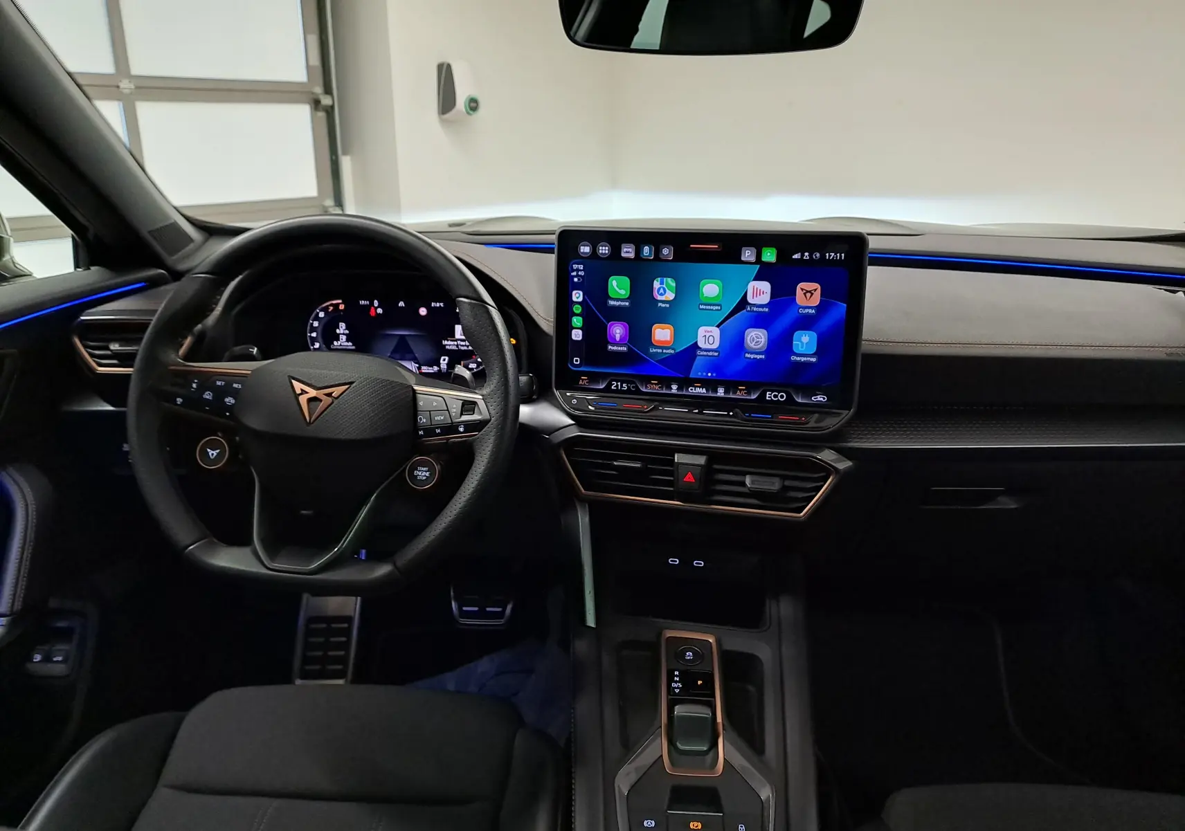 Vue intérieure avant du CUPRA Formentor 1.4 EHybrid avec tableau de bord noir, volant cuir et écran tactile central lumineux.