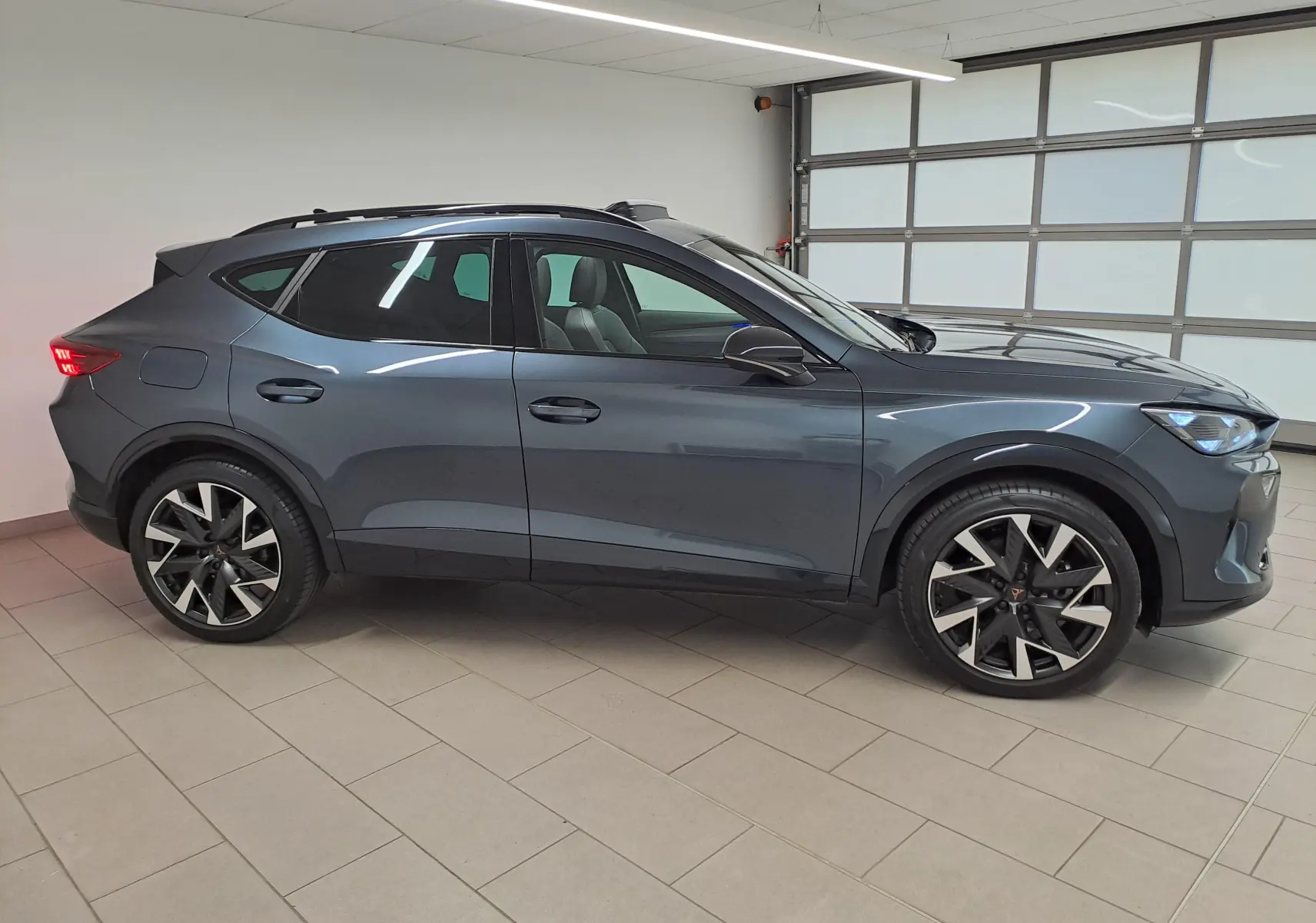 Vue de profil côté gauche d'un CUPRA Formentor gris magnétique avec jantes alliage 19'' et toit ouvrant panoramique.