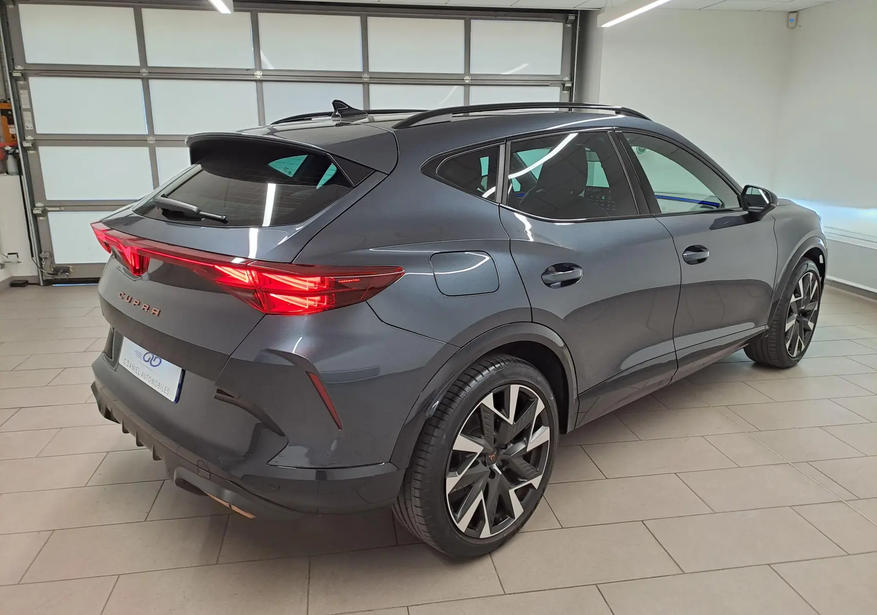 Vue 3/4 arrière droite du CUPRA Formentor gris magnétique avec jantes alliage 19'' et feux arrière Tri-LED allumés.