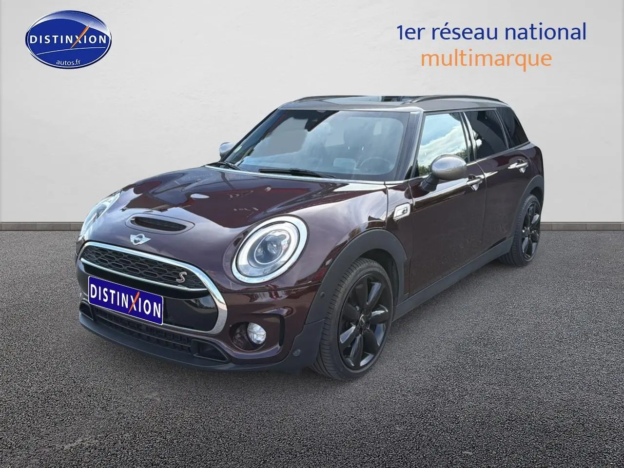 Vue 3/4 avant droite d'une MINI Clubman bordeaux avec calandre chromée et jantes noires.