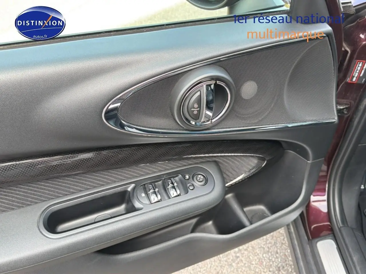 Vue rapprochée de la porte avant gauche bordeaux de la MINI Clubman F54 avec commandes électriques et insert carbone.