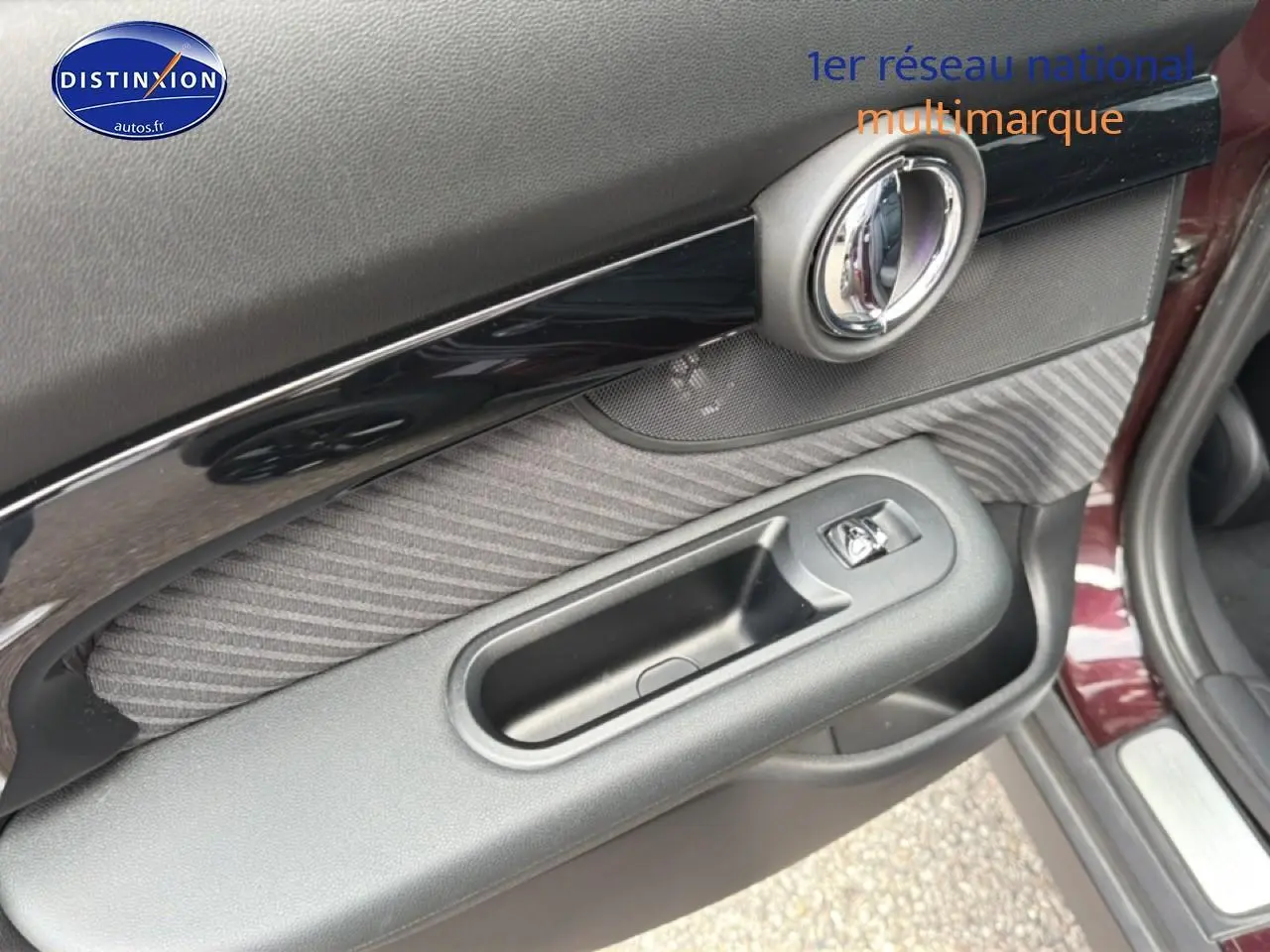Gros plan sur la porte avant gauche bordeaux de la MINI Clubman F54, avec garniture tissu et poignée noire.