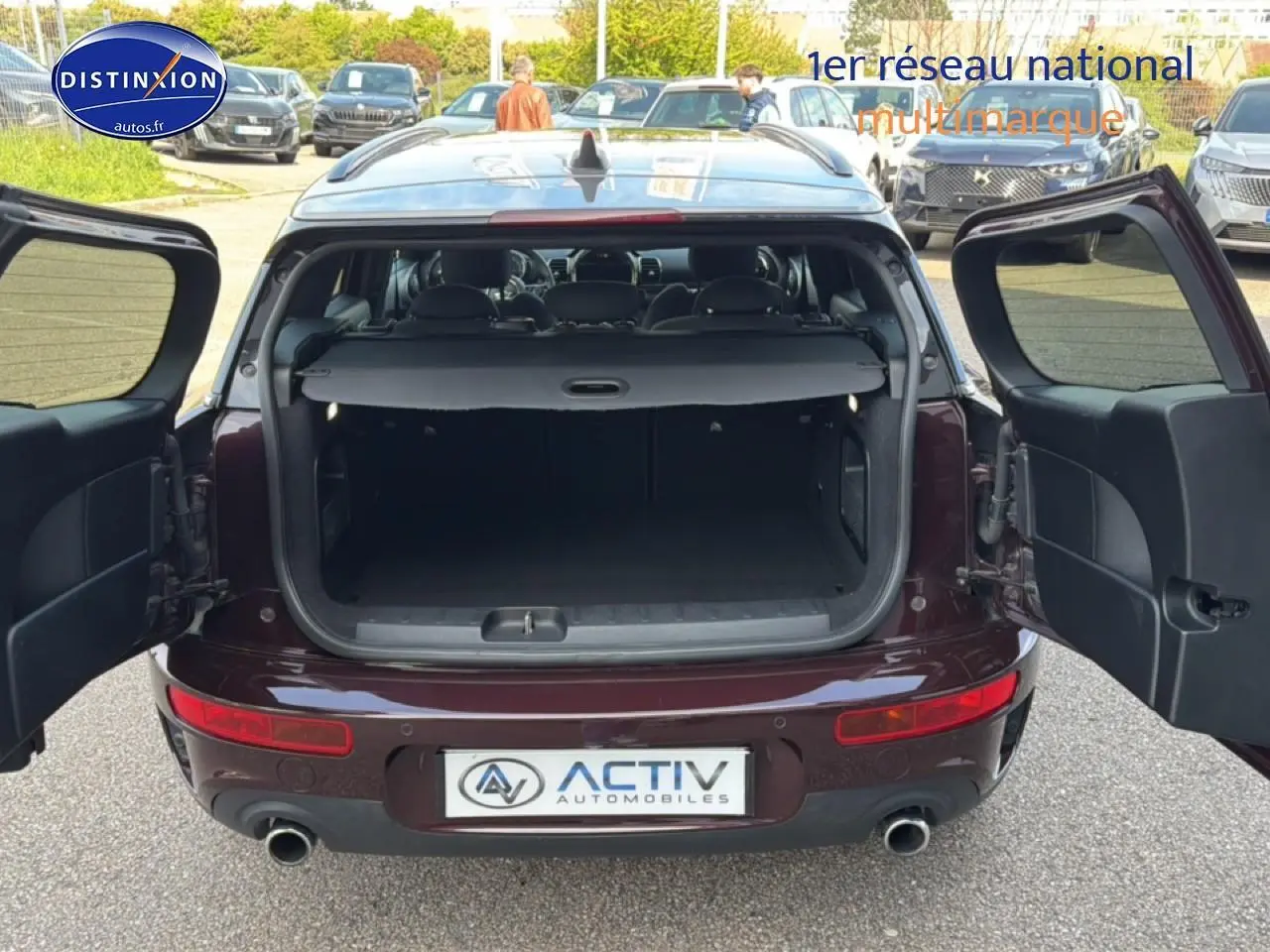 Vue arrière avec portes battantes ouvertes d'une MINI Clubman F54 Cooper SD bordeaux montrant le coffre spacieux.