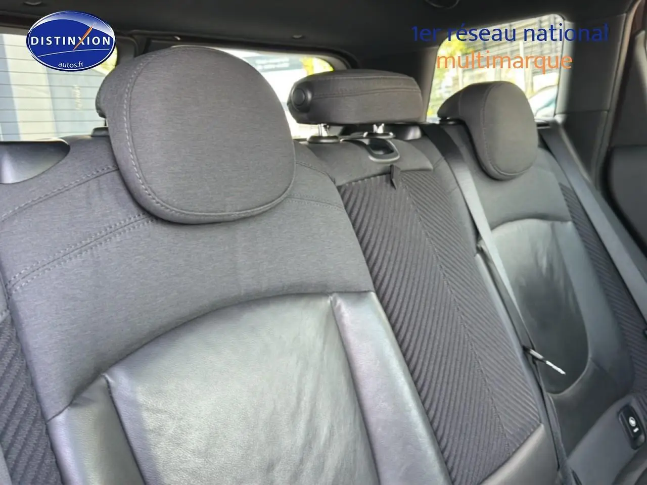 Vue rapprochée des sièges arrière en tissu et cuir noir du MINI Clubman bordeaux, avec appuie-têtes et ceintures visibles.