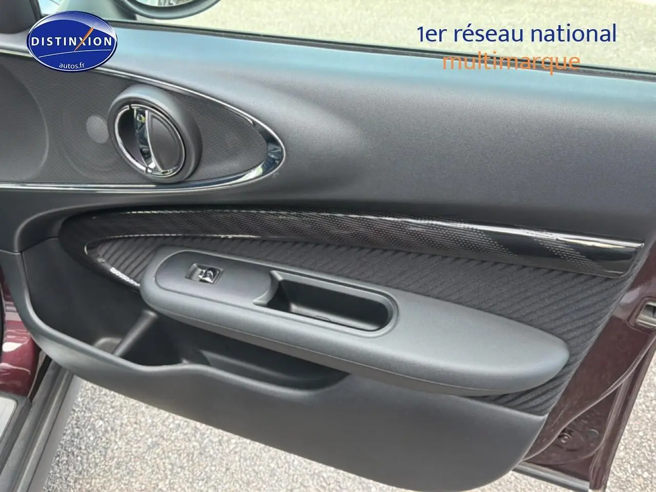 Vue rapprochée de la porte avant gauche bordeaux du MINI Clubman F54 avec insert carbone et poignée chromée.