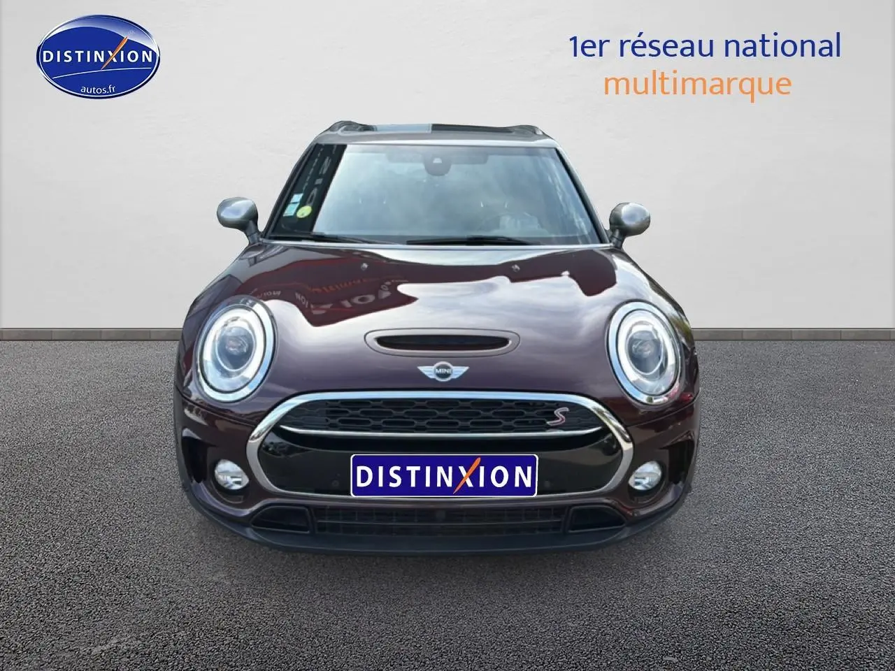 Vue frontale d'une MINI Clubman Cooper SD bordeaux avec calandre chromée et phares ronds LED.