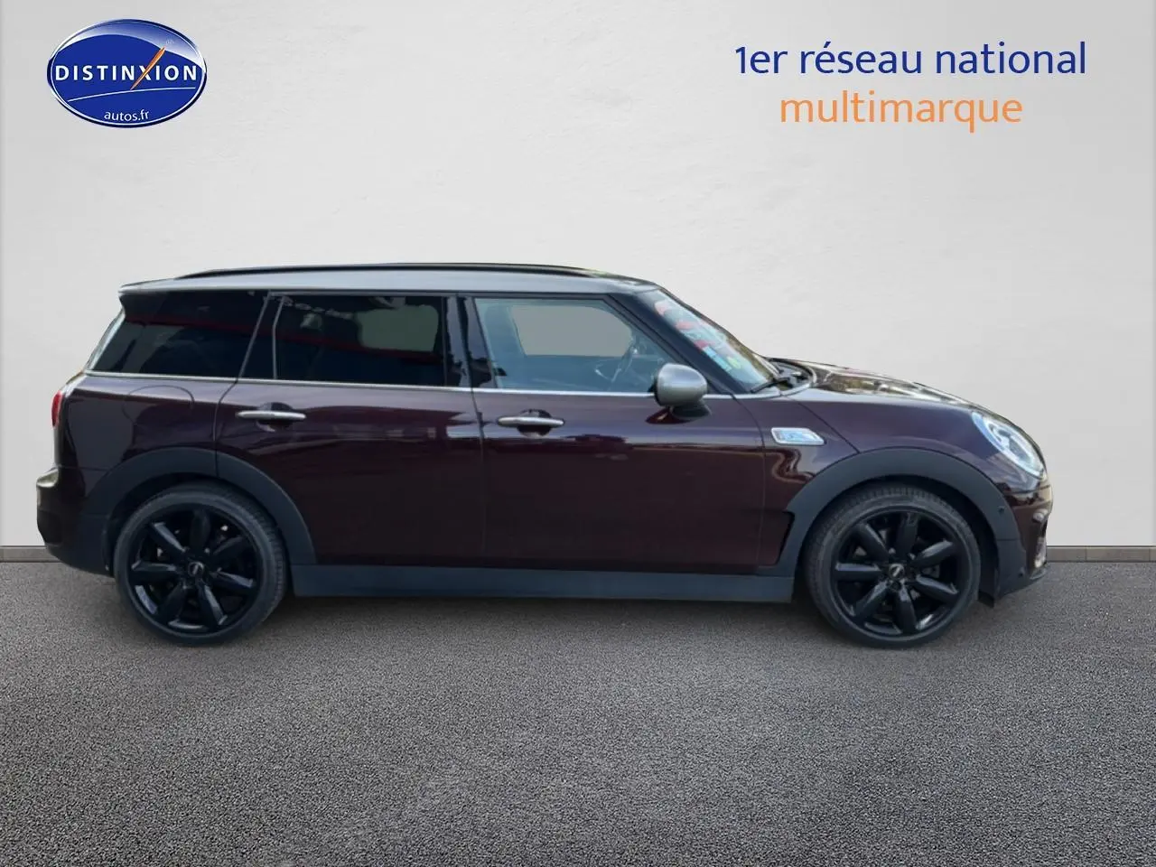 Profil droit d'une MINI Clubman bordeaux avec jantes noires et toit gris sur fond neutre.