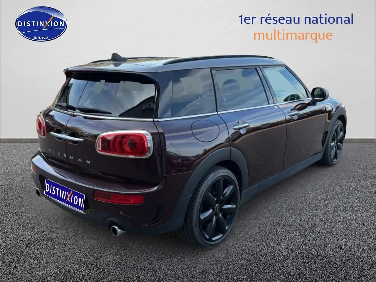 Vue 3/4 arrière droite d'une MINI Clubman Cooper SD bordeaux avec jantes noires et double sortie d'échappement chromée.
