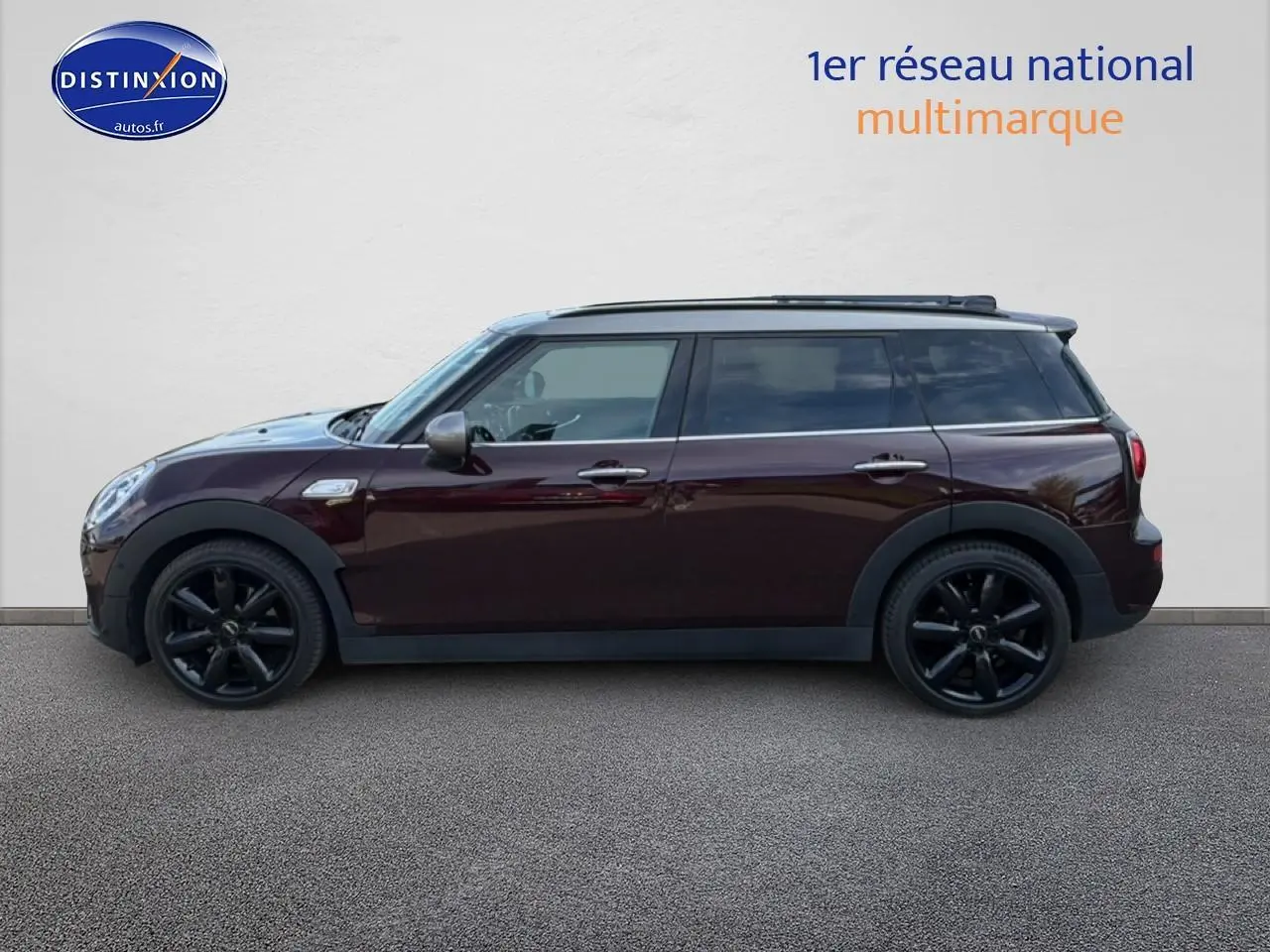 Vue latérale droite d'une MINI Clubman bordeaux avec jantes noires et toit panoramique en verre.