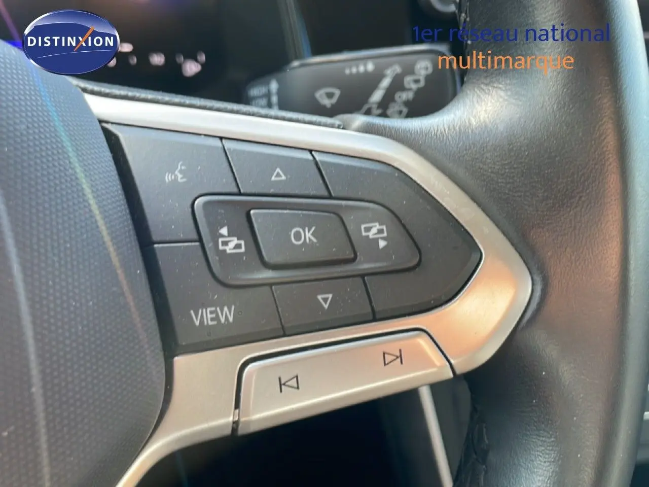Gros plan sur les commandes multifonctions en plastique noir et argent du volant cuir noir d’un Volkswagen Taigo 2022.