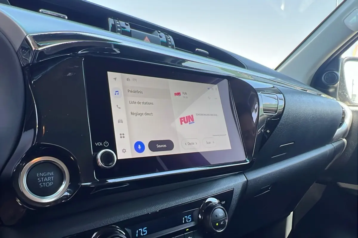 Vue intérieure côté passager du tableau de bord du Toyota Hilux gris atlas, avec écran tactile et bouton start/stop visibles.