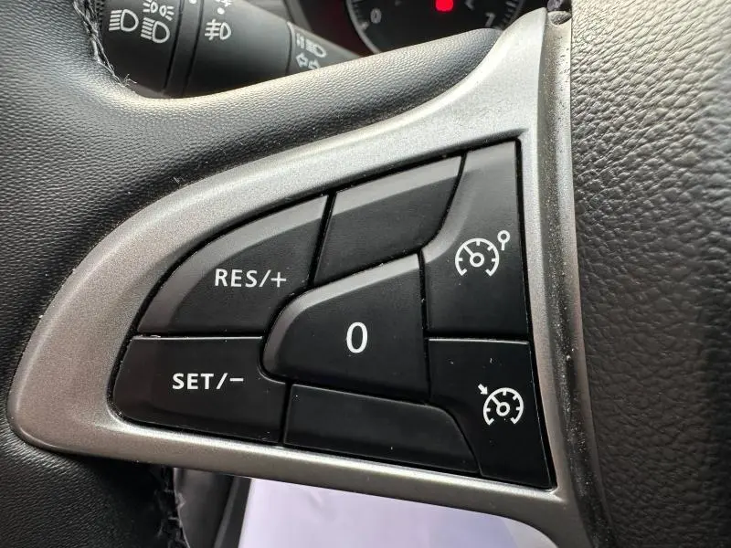 Gros plan sur les commandes du régulateur de vitesse au volant du Dacia Duster blanc 2024, version Extreme 4x4.