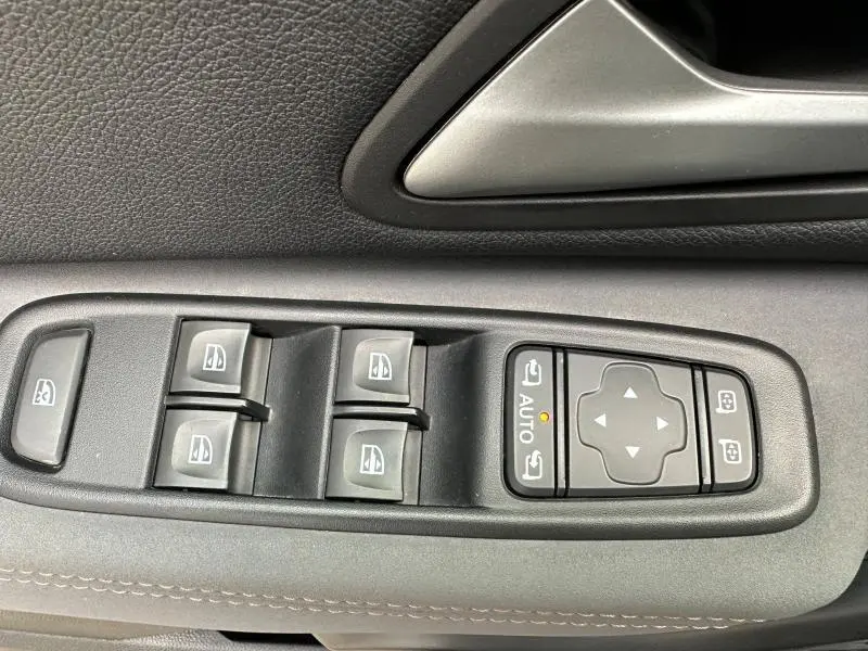Commandes des vitres électriques et rétroviseurs sur la porte côté gauche d'un Dacia Duster blanc Glacier 2024.