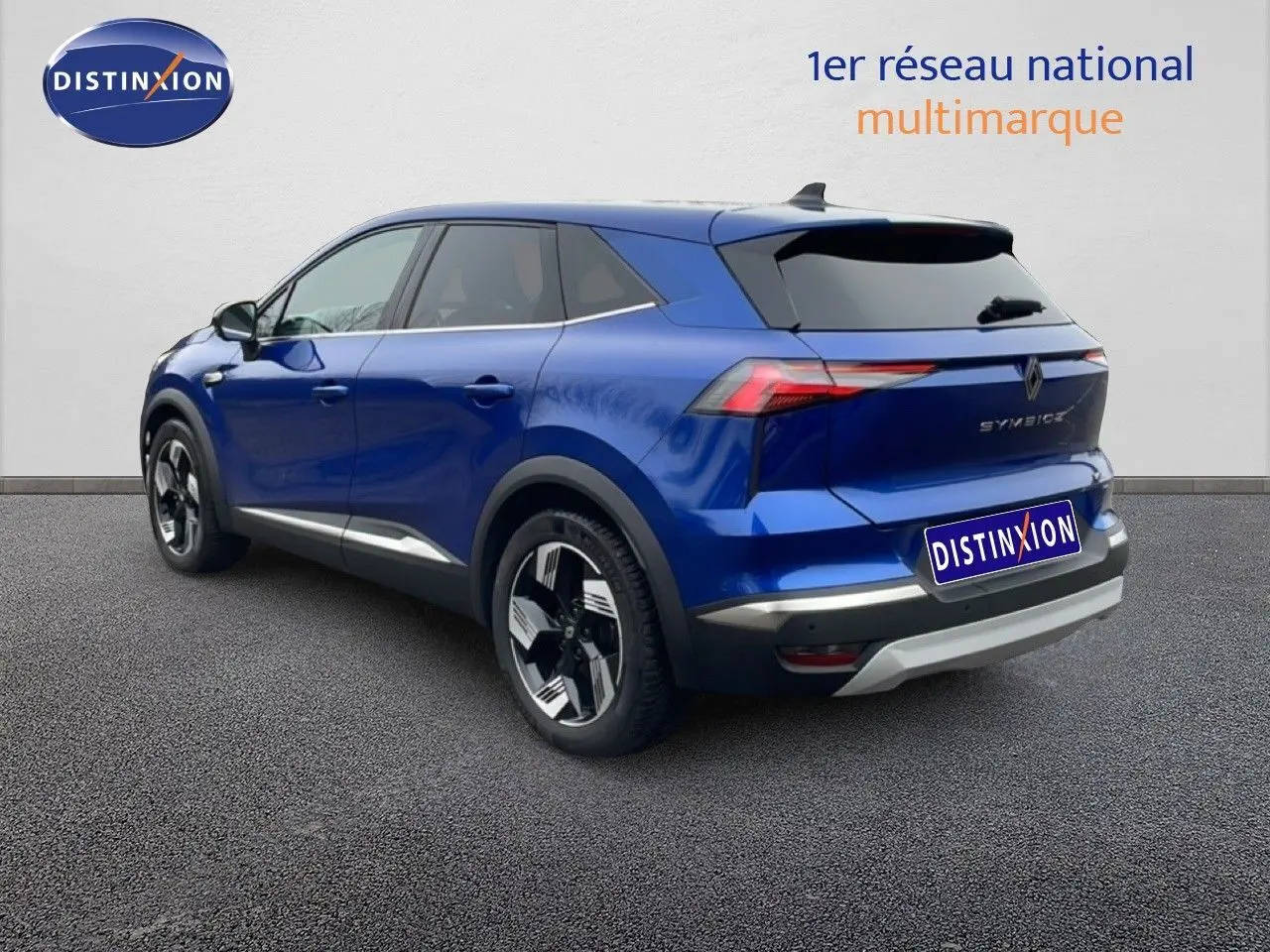 Renault Symbioz E-Tech hybride bleu Iron Metal, vue 3/4 arrière droit avec jantes noires et détails argentés.