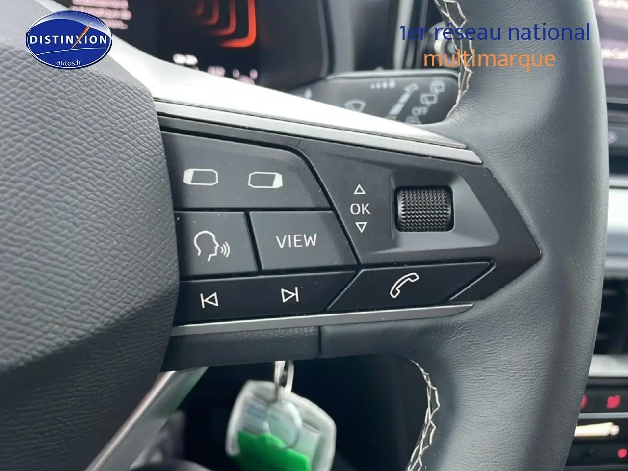 Gros plan sur les commandes noires multifonctions du volant cuir méplat d'une SEAT Arona blanc Nevada 2025.