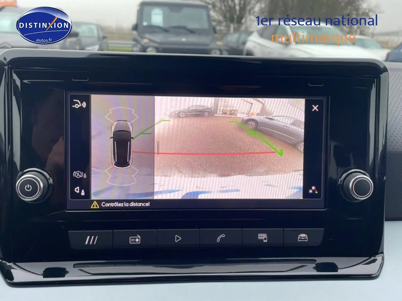 Écran de caméra de recul affichant une SEAT Arona blanc Nevada vue de l'arrière en stationnement.