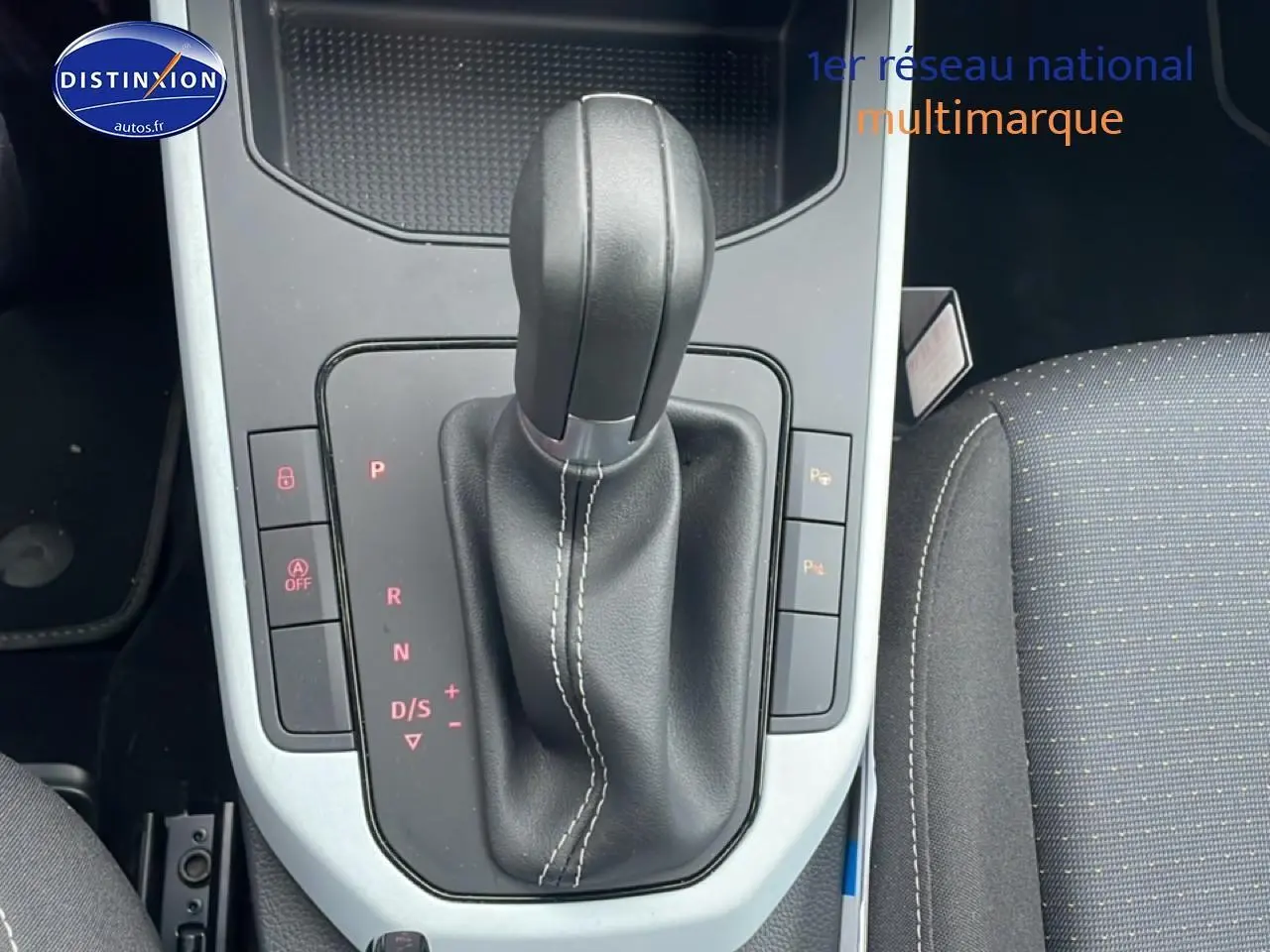 Levier de boîte automatique noir avec coutures blanches, console centrale et siège tissu gris dans une SEAT Arona 2025.